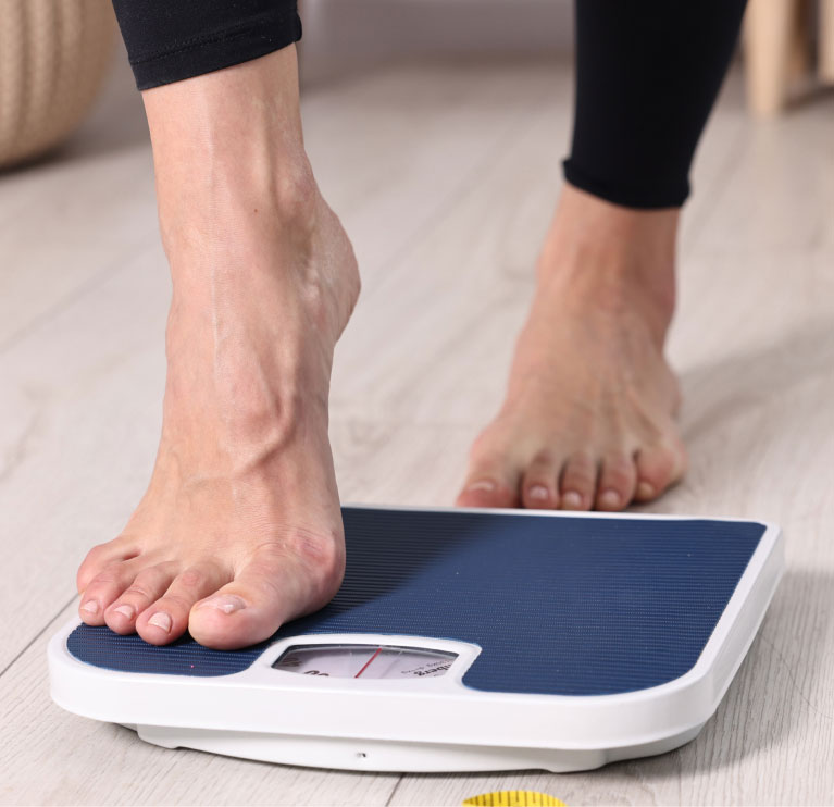 woman stepping on the scale during weight loss plan